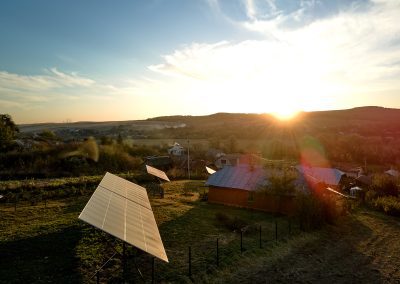 Private home with solar photovoltaic panels mounted on stand-alone frame on backyard ground for generating of clean ecological electric energy in suburban rural town area.