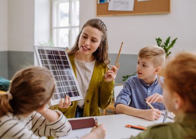 Young teacher with solar panel learning pupils about solar energy.