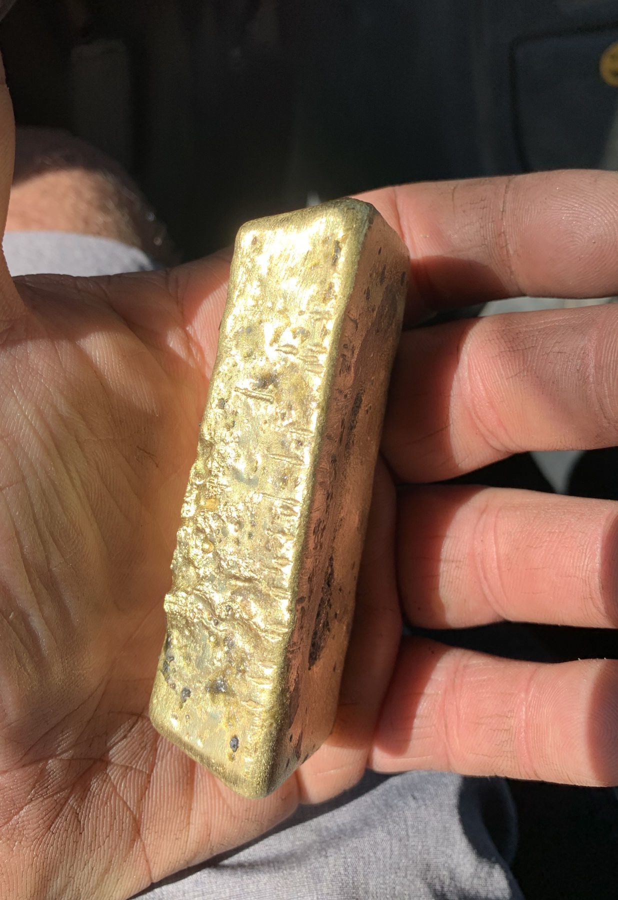 A poured gold bar resting in an open hand